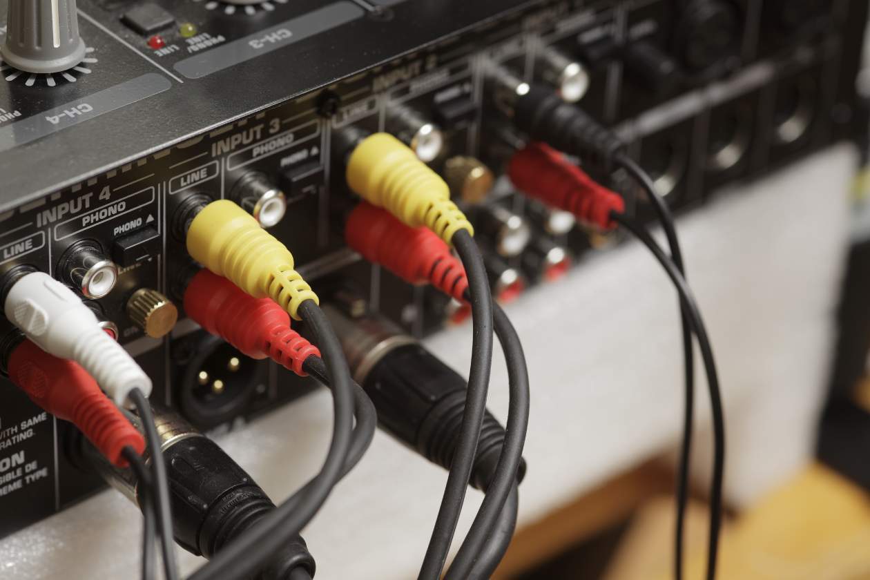 Rear panel of an audio-visual amplifier showing RCA audio and video cables securely connected to labelled input ports, illustrating proper cable connections used in AV equipment maintenance.
